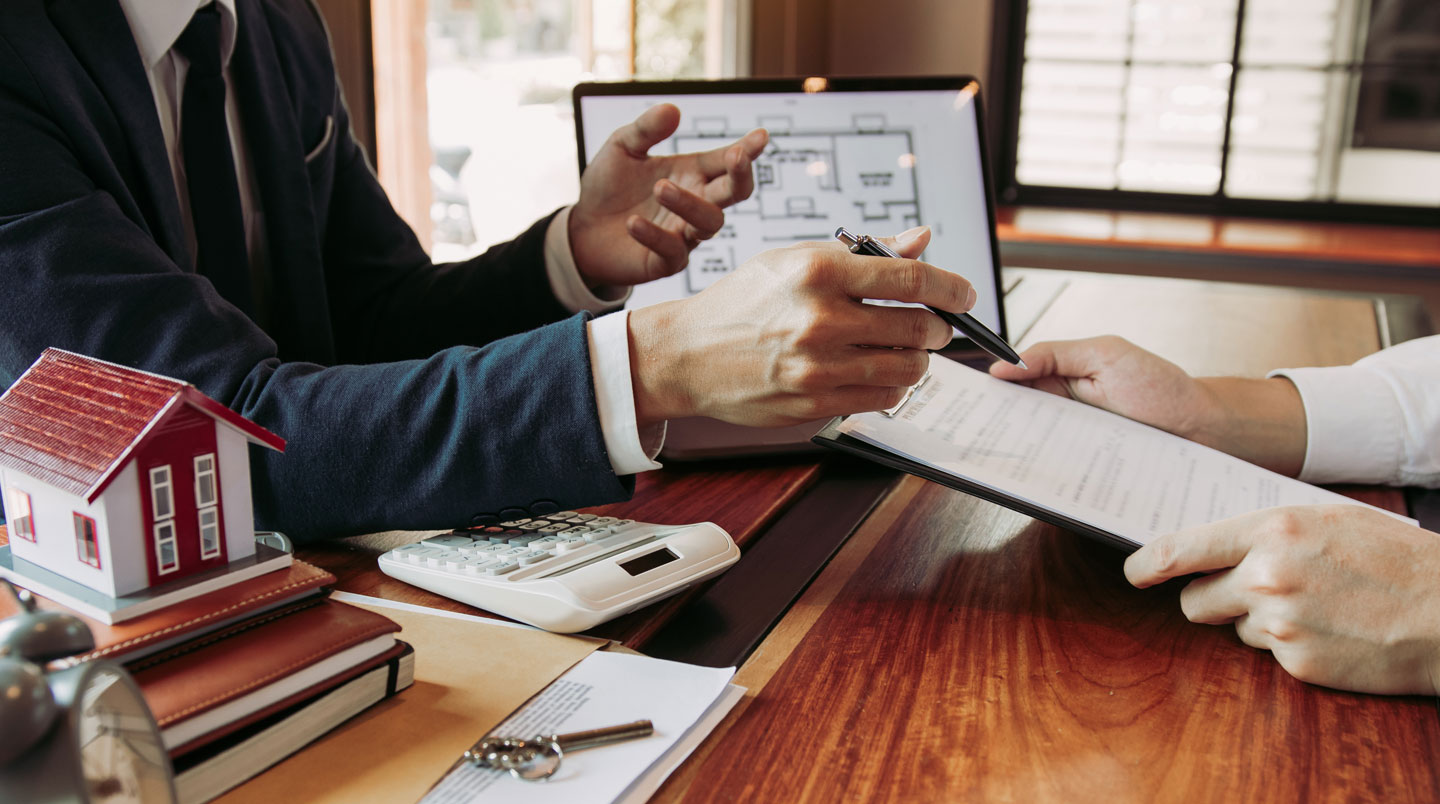 Mains analysant deux propositions d'assurance emprunteur côte à côte sur un bureau en bois clair, avec calculatrice et graphique d'évolution des primes, dans une scène de comparaison documentaire